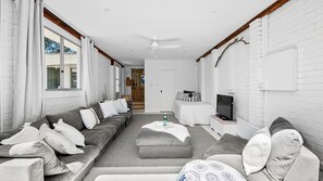 Un salon moderne avec un canapé gris, un téléviseur à écran plat et une grande fenêtre.