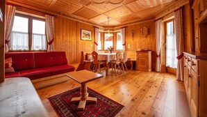 A wooden cabin interior with a red sofa, dining table, and chairs. - Apartment Carolina 185A (Ortisei)