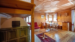 A wooden cabin interior with a dining area, a red sofa, and a wooden table. - Apartment Carolina 185A (Ortisei)