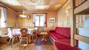 Ein Holzblockbau-Innenraum mit Essbereich, einem roten Sofa und einer Holzbalkendecke.