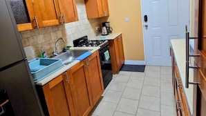 A kitchen with wooden cabinets, a sink, stove, and a refrigerator. - Lovely 2-Bedroom Apartment, Shared Outdoor Pool, 10 minutes walk to downtown  (Roseau)