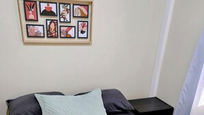 A neatly made bed with a patterned quilt, a light blue pillow, and dark pillows. There is a framed artwork above the bed. - Lovely 2-Bedroom Apartment, Shared Outdoor Pool, 10 minutes walk to downtown  (Roseau)