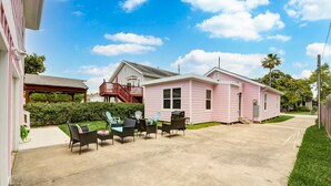 A pink house with a covered patio and outdoor furniture.