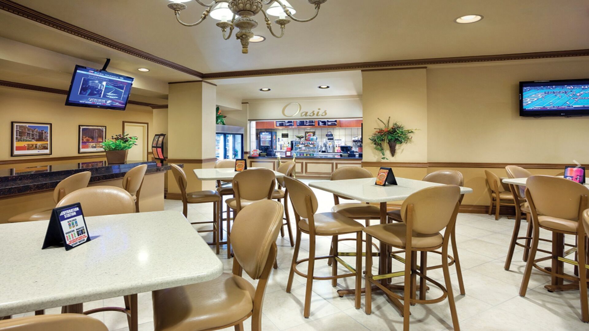 A hotel lobby with multiple seating areas, a reception desk, and a restaurant named 'Oasis' in the background.