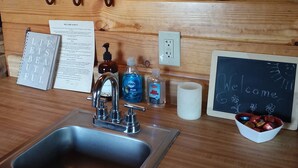 A wooden counter with a sink, a chalkboard with 'Welcome' written on it, and a bowl of chocolates. - Comfy cabin for two close to Grand Canyon and many Northern Arizona attractions (Williams)