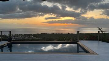 Une piscine sur le toit offrant une vue sur la mer et un magnifique coucher de soleil.
