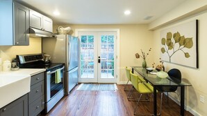 Une cuisine moderne avec un coin repas, comprenant une table et des chaises en verre, un réfrigérateur et une cuisinière.