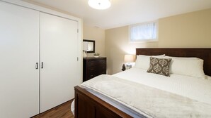 Une chambre à coucher avec un lit, une armoire, une table de chevet, une lampe et une fenêtre.