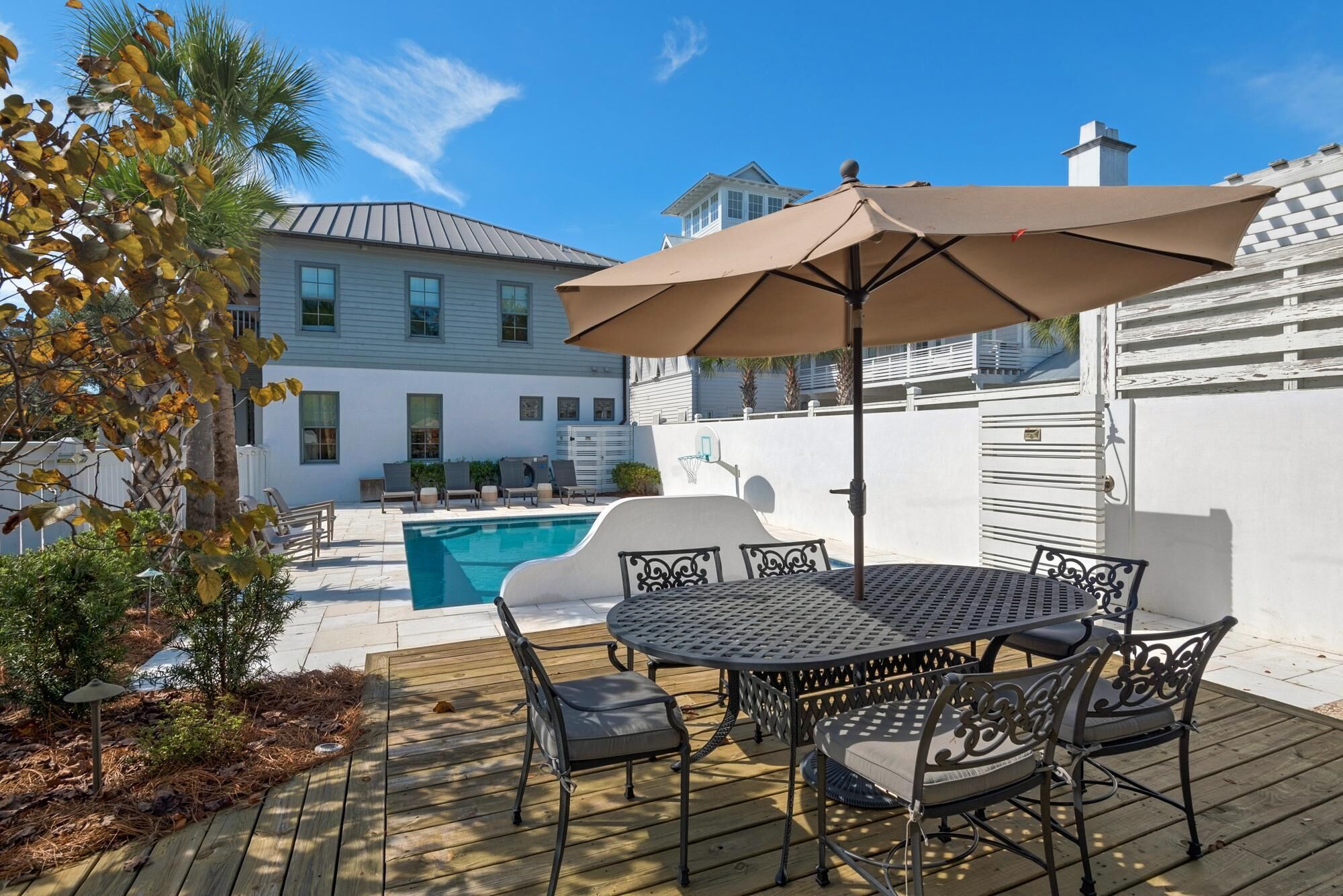 Een houten terras met een pooltafel, stoelen en een grote parasol.