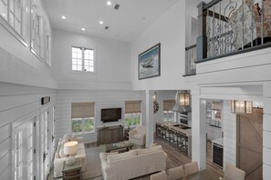 A spacious living area with a large TV, comfortable seating, a kitchen with bar seating, and a fireplace.