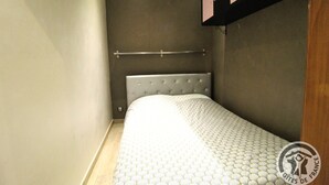 A small, narrow room with a single bed, a headboard, and a shelf above it. - Le Rivat - COMMUNAY - Gîte (COMMUNAY)
