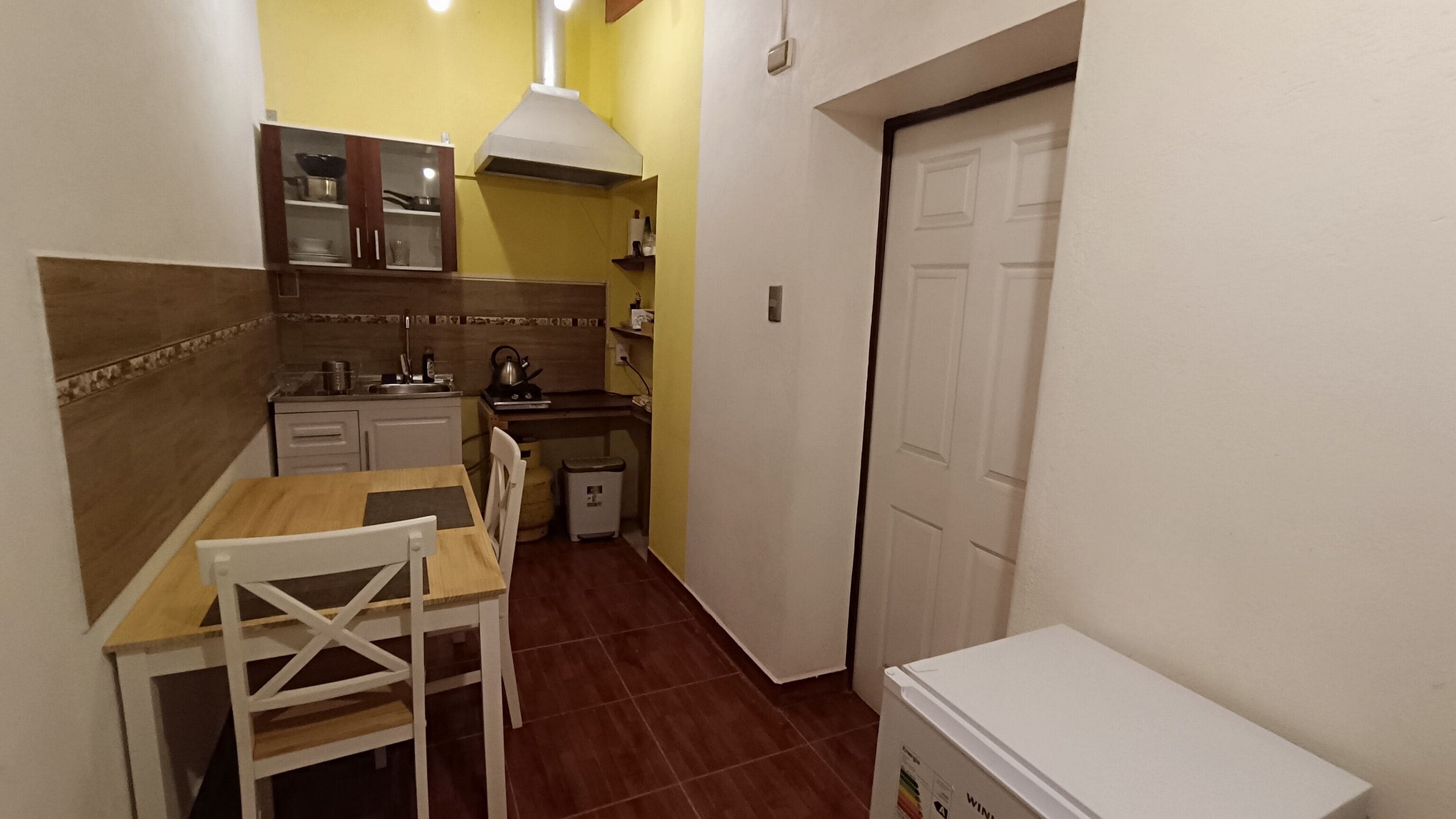 Une cuisine de taille réduite comprenant une table à manger, des chaises, une cuisinière et un évier.