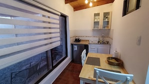 A compact kitchen with a window, a sink, a kettle, and a small refrigerator. - Yurak Apart Hotel (San Pedro de Atacama)