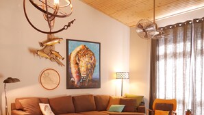 Ein modernes Wohnzimmer mit einem Ecksofa, einem runden Couchtisch, Holzboden und einem farbenfrohen Teppich.