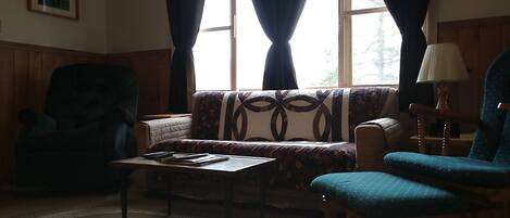 A living room with a sofa, two armchairs, a coffee table, and a lamp.