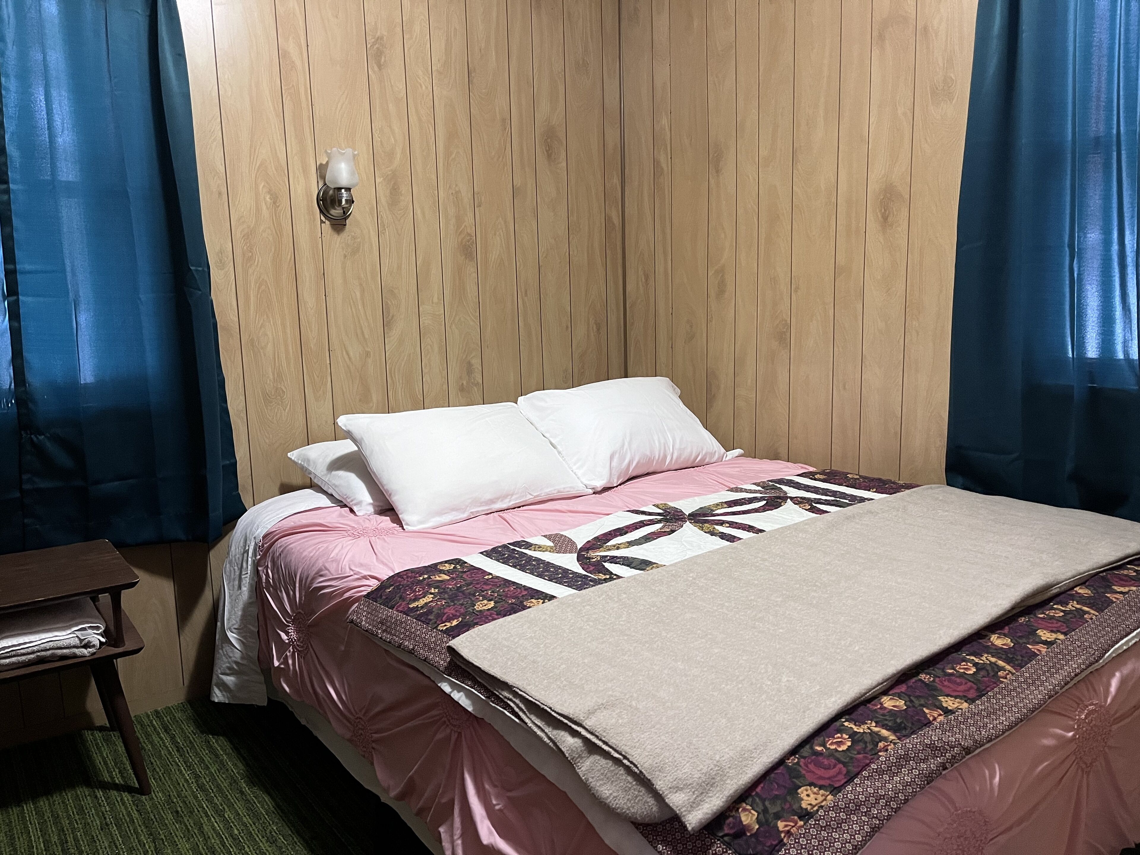 Una cama bien hecha con colcha floral, una mesita de noche y un cabecero de madera.