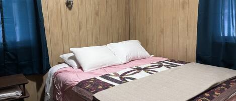 Una cama bien hecha con colcha floral, una mesita de noche y un cabecero de madera.