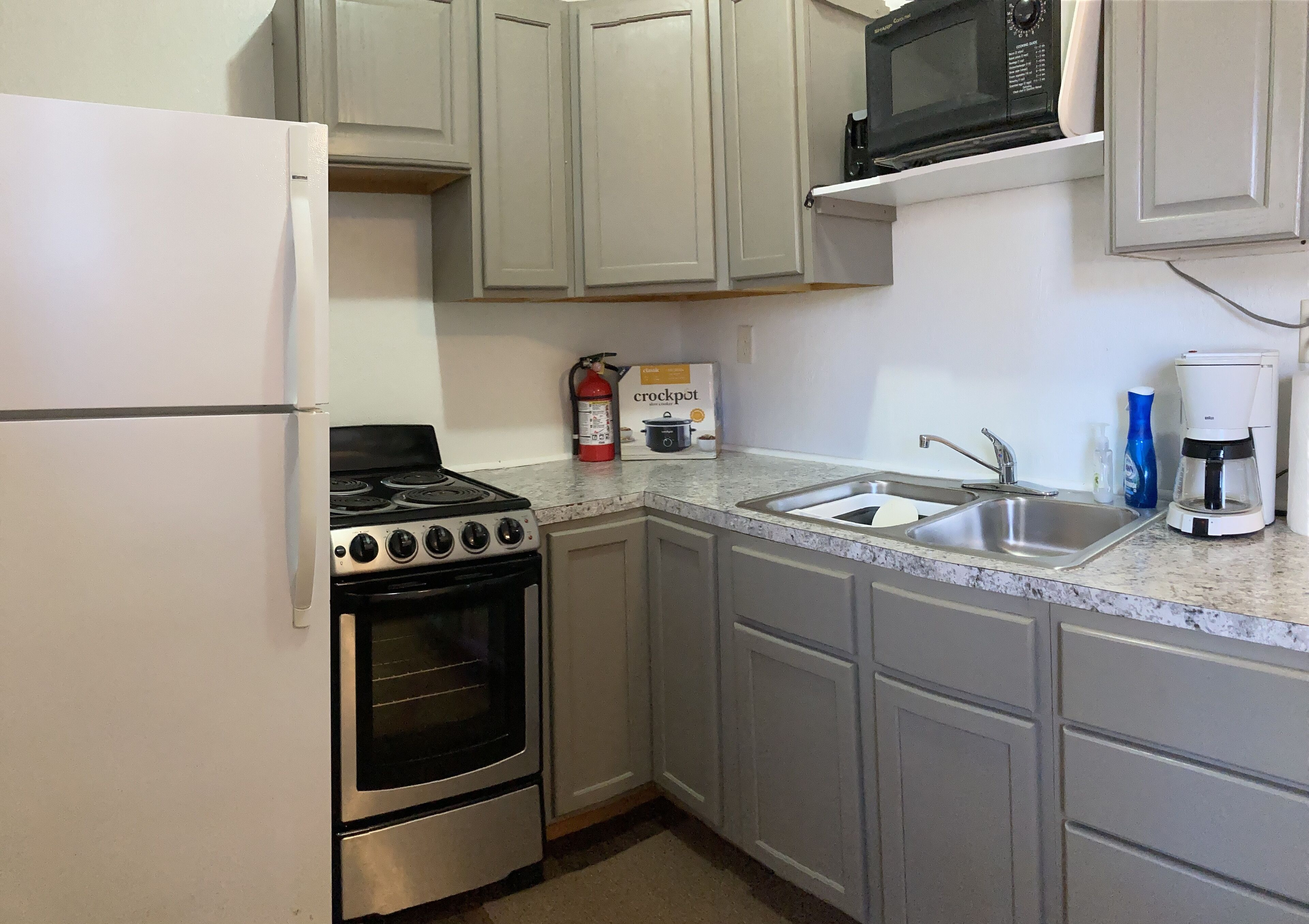 A compact kitchen with a stove, oven, microwave, and sink.