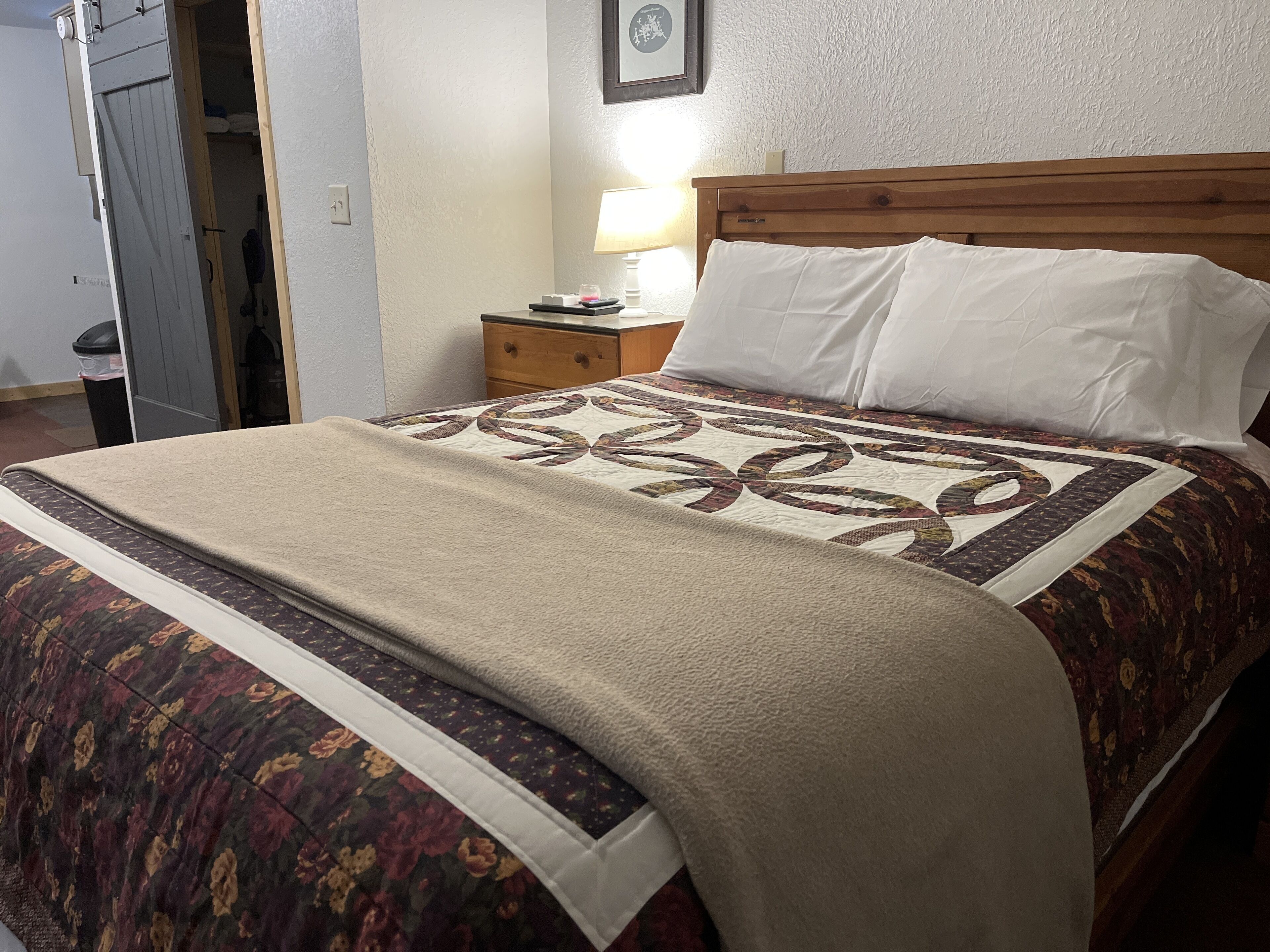 A neatly made bed with a floral-patterned bedspread and a beige blanket.