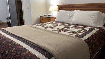 A neatly made bed with a floral-patterned bedspread and a beige blanket.