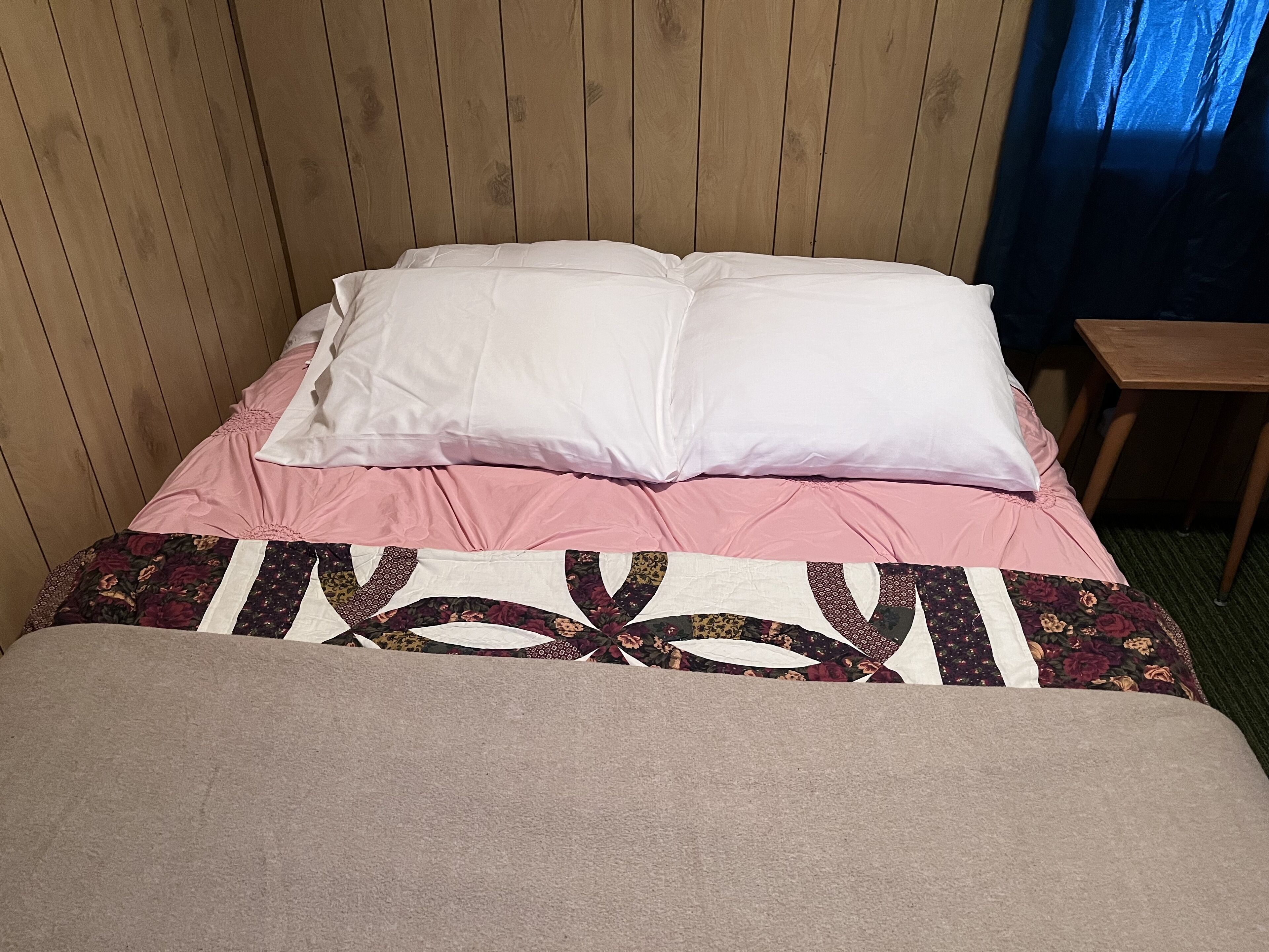 A bed with a floral-patterned bedspread and a wooden headboard.