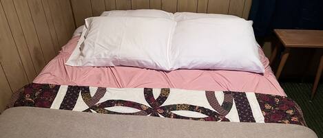 A bed with a floral-patterned bedspread and a wooden headboard.
