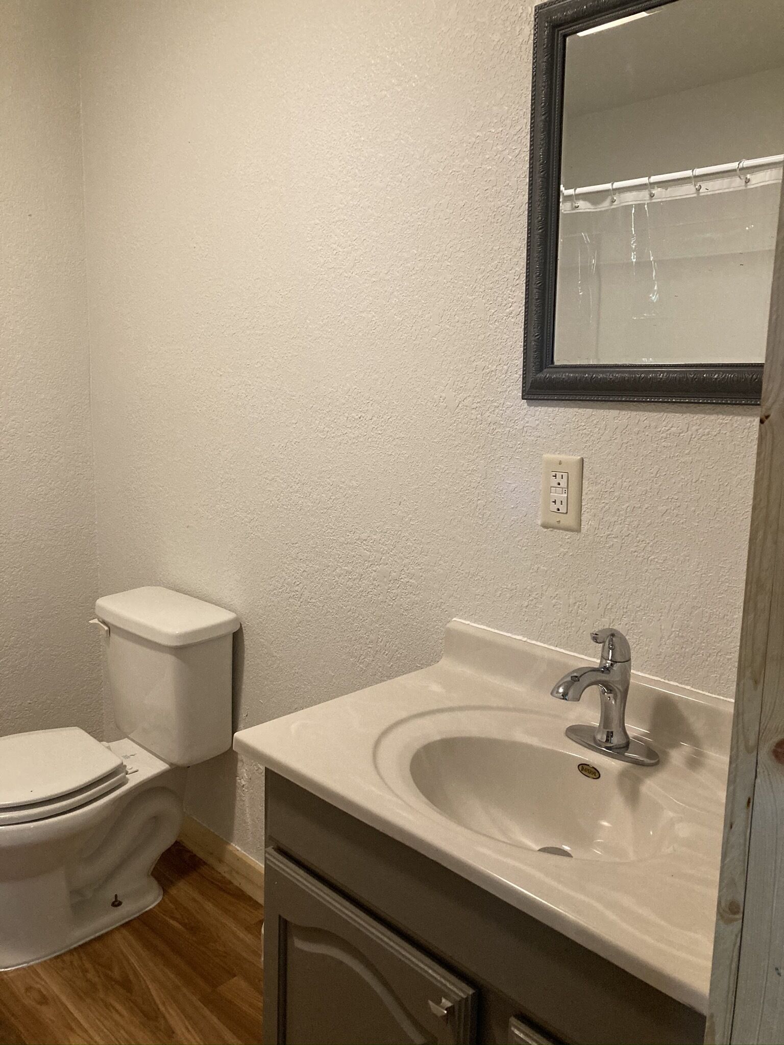 A bathroom with a toilet, sink, and mirror.