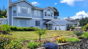 A two-story house with a garage, a front porch, and a well-maintained garden with various plants and flowers.