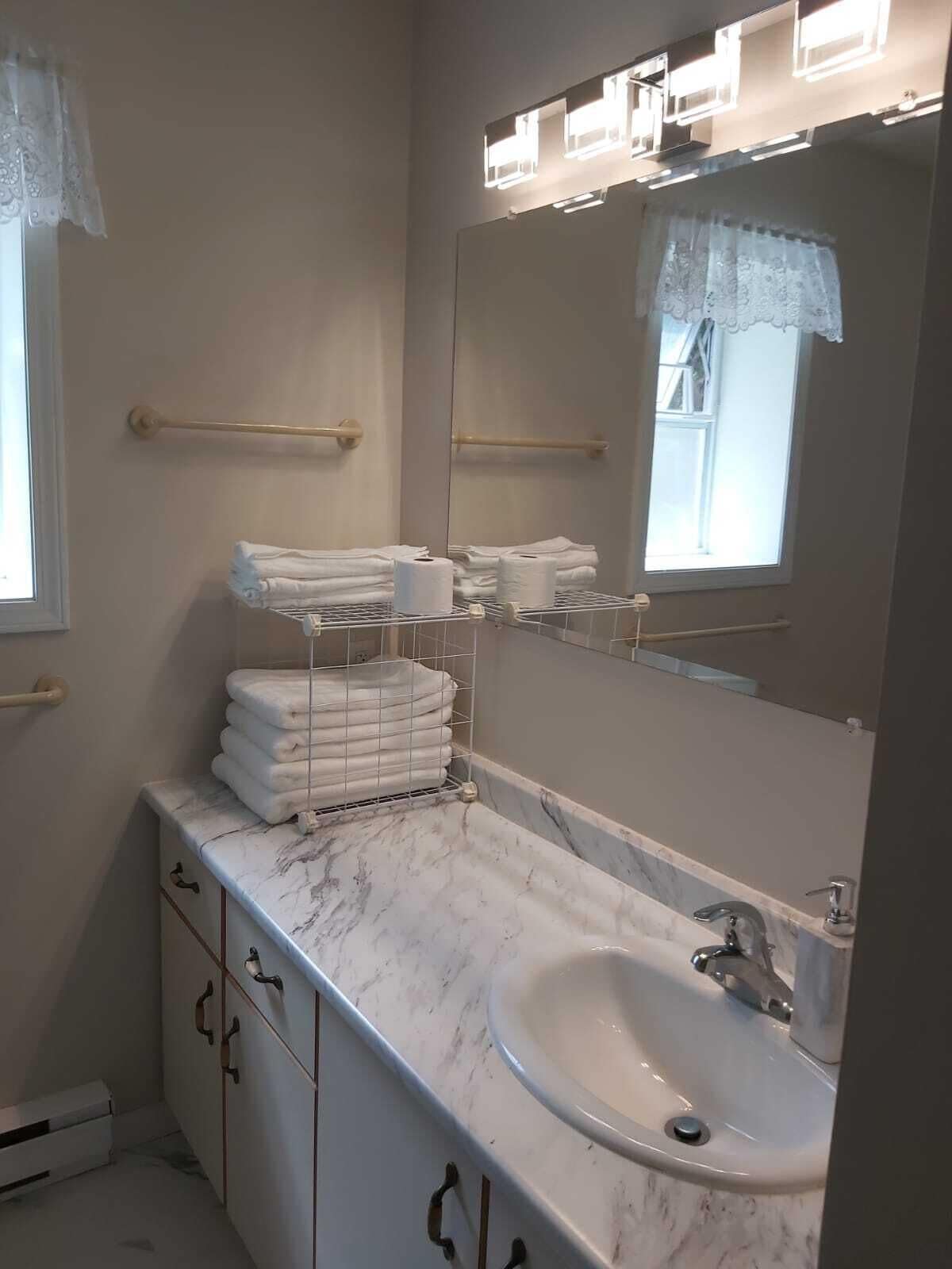 A bathroom with a marble countertop, a sink, a mirror, and a towel rack.