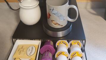 Une machine à café Keurig, avec une tasse et une cafetière, posées sur un support noir.