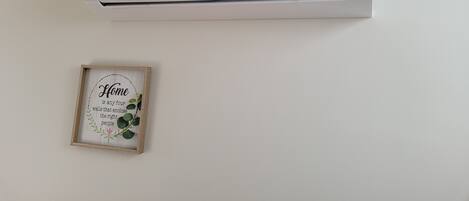 A wall-mounted air conditioner with a framed quote below it.