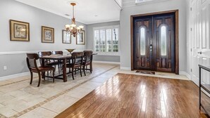 A spacious dining area with a wooden table and chairs, a chandelier, and framed artwork on the walls. - Villa Encore (Cape Coral)