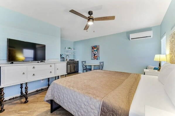 A bedroom with a bed, a desk, a chair, a television, and a ceiling fan. - Private Space Bishop Arts (Dallas)