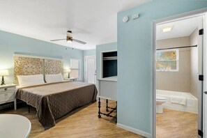 A bedroom with a bed, nightstands, a ceiling fan, a bathroom with a bathtub, and a window with artwork. - Private Space Bishop Arts (Dallas)