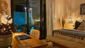 Quarto moderno com escrivaninha de madeira, laptop e cama com colcha estampada.