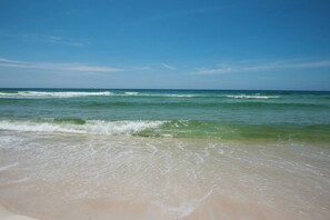 A beach with clear blue water and waves.