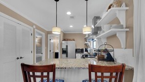 A kitchen with granite countertops, two wooden chairs, a refrigerator, a microwave, and a sink. - 2 complimentary Bikes! Directly on 30A! Beach access across the street! (Santa Rosa Beach)
