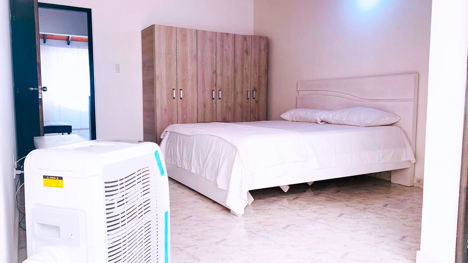 Un dormitorio con cama, armario y equipo de aire acondicionado.