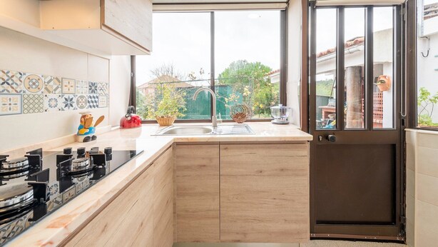 A modern kitchen with a large window, a sink, and a stove.