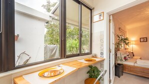 A room with a wooden counter, a window, a bed, and a plant.