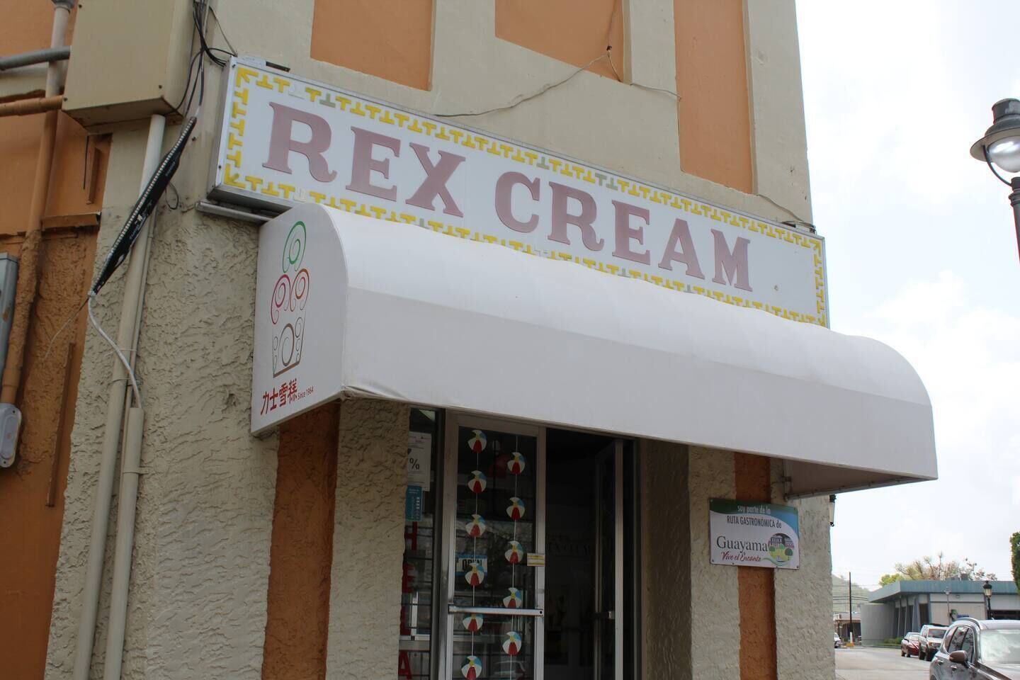 Ein Schaufenster mit einem Schild mit der Aufschrift "REX CREAM" und einem Blick in den farbenfroh dekorierten Innenraum.