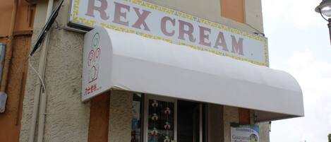 Ein Schaufenster mit einem Schild mit der Aufschrift "REX CREAM" und einem Blick in den farbenfroh dekorierten Innenraum.