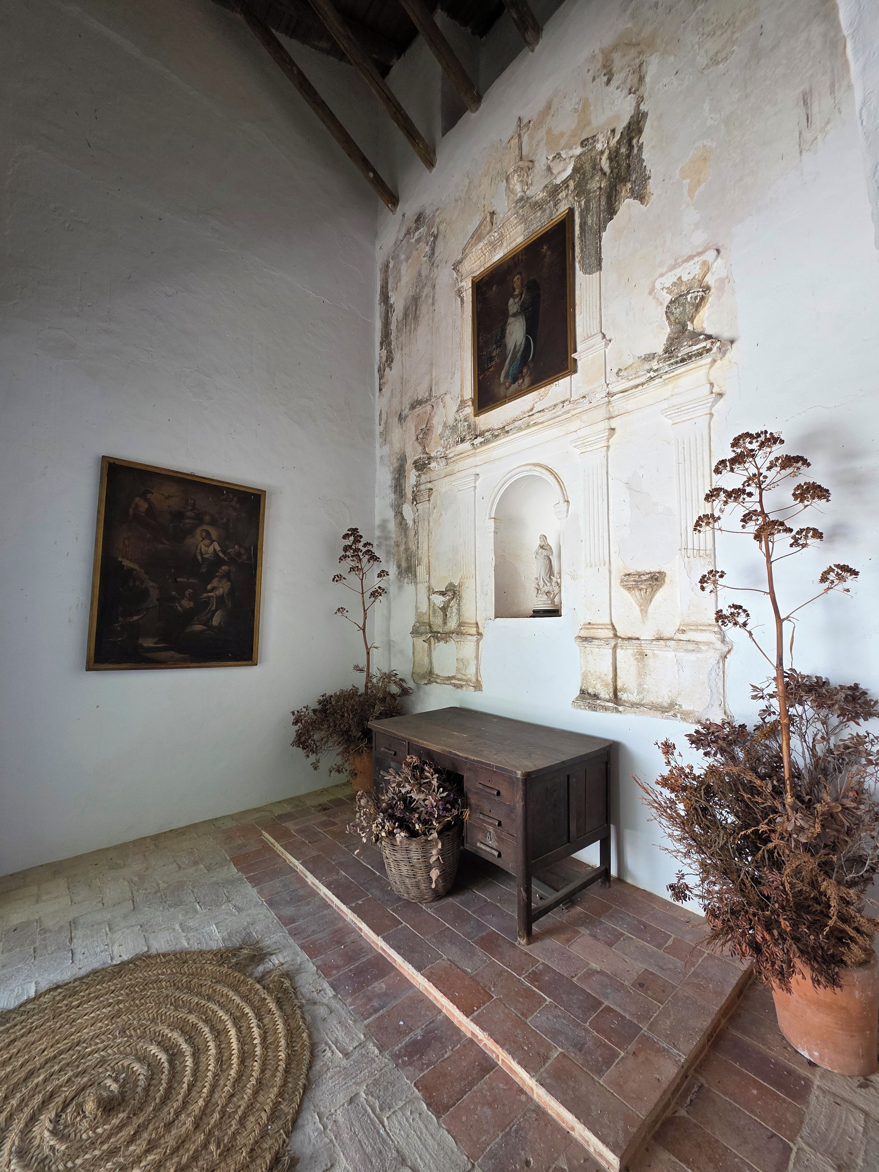 Une pièce au décor rustique, comprenant un banc en bois, un tableau accroché au mur et des plantes en pot.