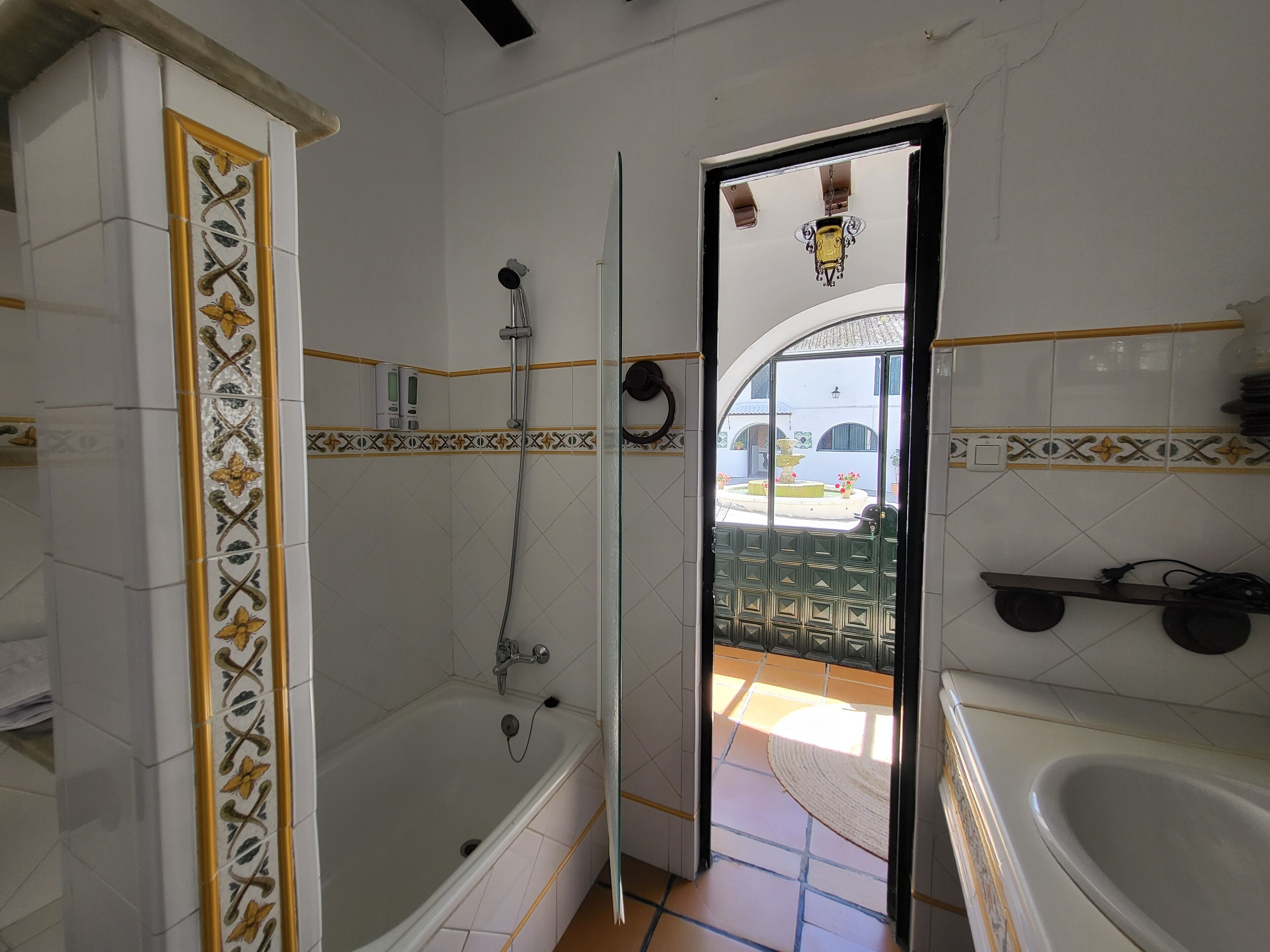A bathroom with a bathtub, shower, and a glass door leading to an outdoor area.