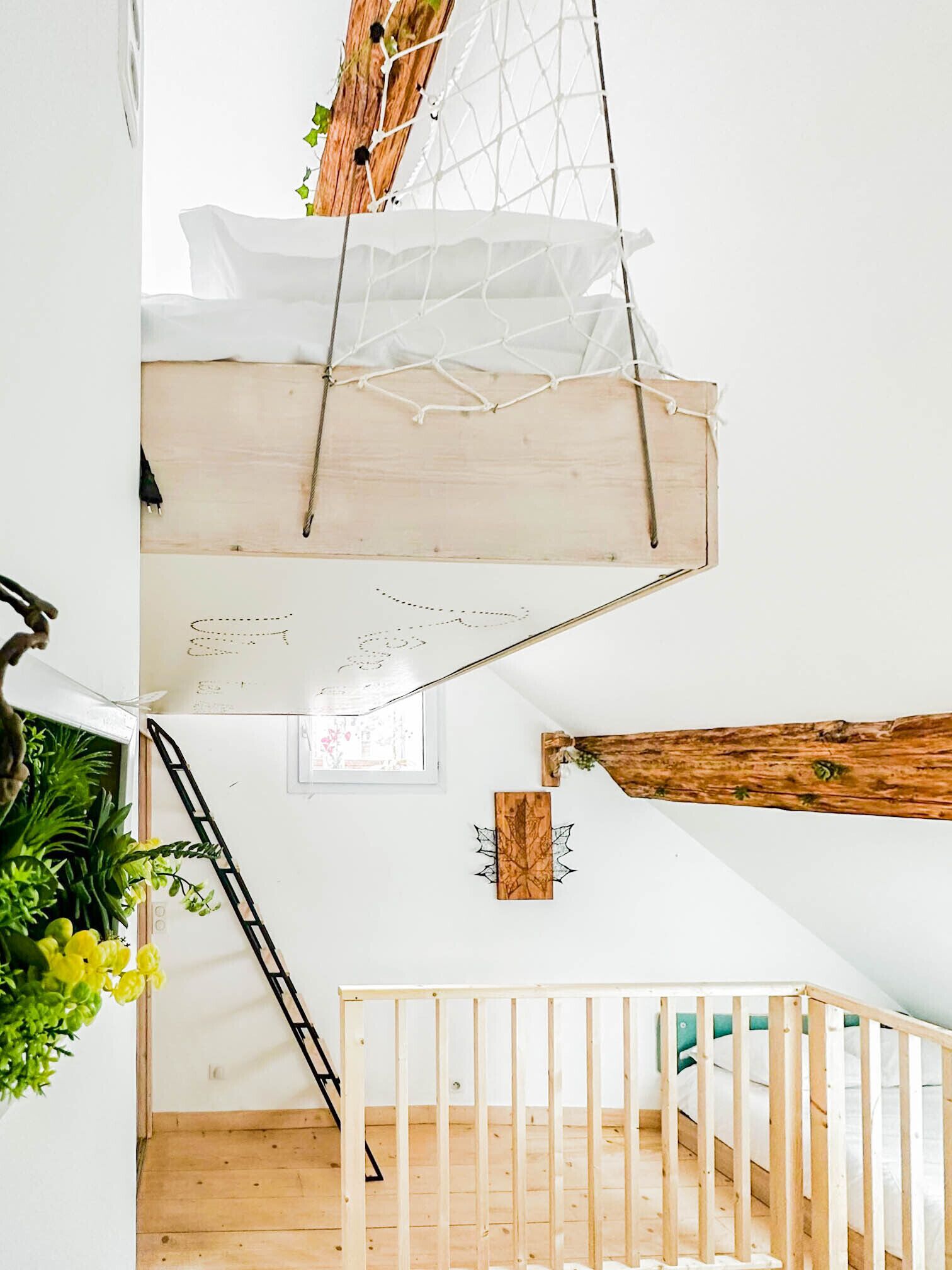 A multi-level wooden interior with a staircase, a hanging net, and a ladder.