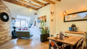 A cozy, well-lit dining area with a wooden table, chairs, and a modern kitchen in the background. - Love island romantique rue carnot (Annecy)
