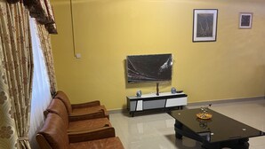 Ein Wohnzimmer mit einer Couch, einem Couchtisch, einem Fernseher und einem kleinen Schrank.