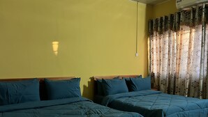 Ein Zimmer mit zwei Betten, gelben Wänden und einem Fenster mit gemusterten Vorhängen.