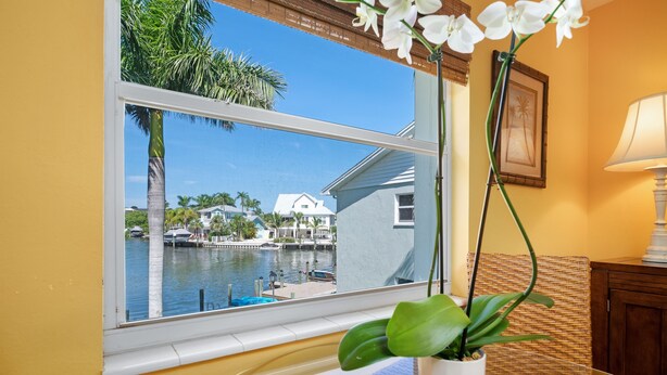 A room with a view of a water body, a potted plant, and a lamp.