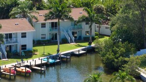 A multi-story building with balconies, a dock, and a small boat.
